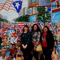 Students pose in front of a mural.